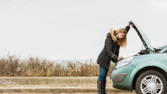 Femme regardant batterie voiture Femme regardant batterie voiture